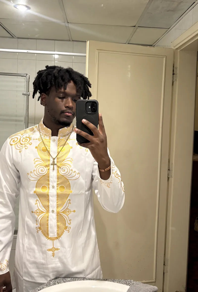 A second mirror selfie of the site owner in the white and gold embroidered outfit and cross necklace.